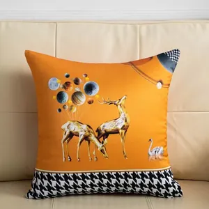 Detailweergave van oranje kussenhoes met gouden hert en klassiek pied-de-poule patroon.