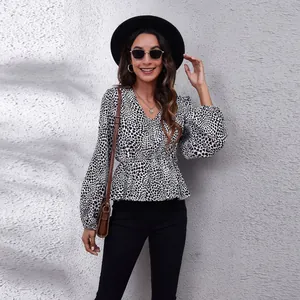 Detailed shot of woman in printed V-neck blouse with stylish lantern sleeves and waist tie