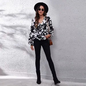 Full body shot of a woman in a floral V-neck top with lantern sleeves and black trousers.