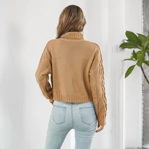 Back view of a woman wearing a tan cable knit turtleneck sweater and light blue jeans