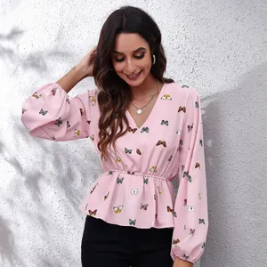 Detail showing the pink V-neck lantern sleeve blouse featuring a vibrant butterfly pattern print