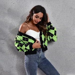 Model wearing a vibrant green and black argyle patterned knit cardigan against grey wall