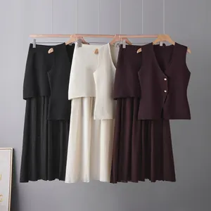 Detailed view of three-color knit vest and pleated skirt sets displayed on a clothing rack