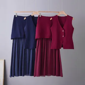 Close-up view of elegant knit vest and pleated skirt sets in navy blue and burgundy colors.