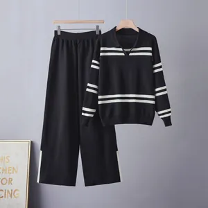 Two-piece black knitted lounge set with white striped details hanging against a gray wall