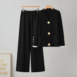 Ensemble élégant en tricot noir deux pièces avec de grands boutons dorés et pantalon large.