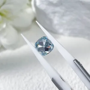 Professional macro shot of a cushion cut blue lab-grown diamond held by tweezers