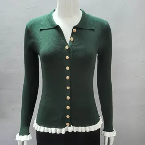 Detailed view of dark green ribbed cardigan with gold buttons and white ruffle trim