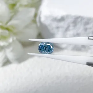 Cushion cut blue lab-grown diamond held by tweezers on a minimalist white background.