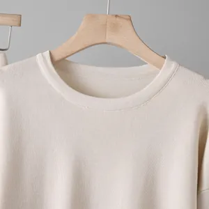 Primer plano del cuello redondo de un jersey de punto color crema en una percha.