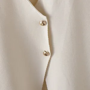 Detailed macro view of cream knitted vest top featuring irregular gold button accents