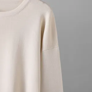 Primer plano de un suéter de punto beige que muestra la textura fina y el cuello redondo