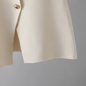 Macro detail of high-quality cream knit fabric texture featuring a round gold button