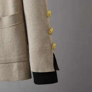 Gros plan de trois boutons dorés gaufrés sur la manche fendue d'un cardigan en maille beige