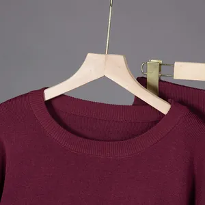 Detail shot of a burgundy knit sweater with a ribbed round neckline and soft fabric.