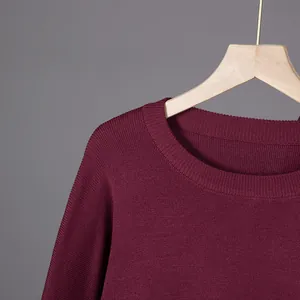 Detailed view of burgundy knit sweater featuring a classic round neck and fine fabric texture