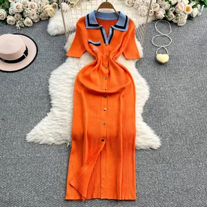 Vista detallada de un vestido polo de punto naranja con accesorios de verano sobre una alfombra.