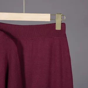 Detailed close-up view of the ribbed waistband on a maroon knitted garment hanging on a hanger