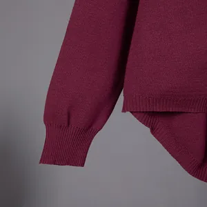Close-up detail of a minimalist burgundy knit sweater showing ribbed cuff and hem texture