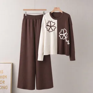Detail of color-block knit sweater and brown wide-leg pants set with floral patterns.