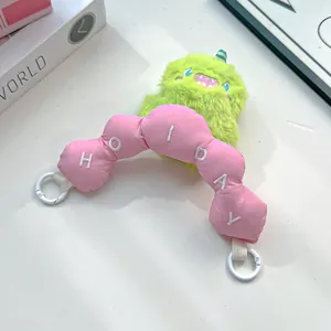 Close-up of cute green plush monster charm with pink embroidered Holiday handle