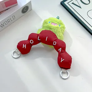 Detail of cute green monster plush and red HOLIDAY embroidered padded bag strap