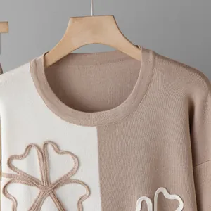 Detailed view of beige colorblock knit sweater with raised floral pattern texture