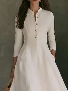 Detail view of white linen dress featuring a stand collar and elegant half placket.