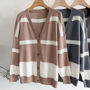 Close-up view of three stylish striped V-neck knitted cardigans on wooden hangers