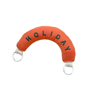 Orange padded crescent bag handle accessory with green embroidered HOLIDAY text and rings
