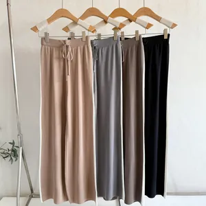 Close-up of four colors of wide-leg knit trousers with sporty side stripes and drawstring