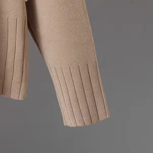 Detailed macro shot of the ribbed cuff and knit texture on a tan knitted pullover top