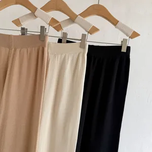 Detailansicht von Strickhosen mit weitem Bein in drei Farben an Holzbügeln