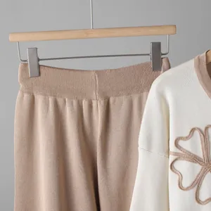 Close-up detail of soft beige knitted wide-leg pants and floral embroidered top.
