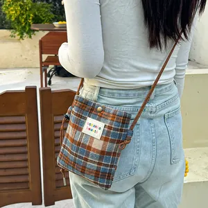 Detail view of a casual checkered woolen crossbody bag with a colorful patch label.