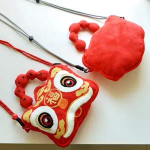 Close-up of red plush bags with traditional lion dance embroidery and handle details.