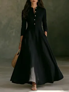Detail of a vintage black linen maxi dress with mandarin collar and gold buttons.