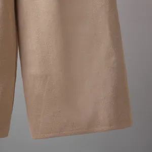 Close-up detail showing the fine knitted fabric texture of camel wide-leg pants.