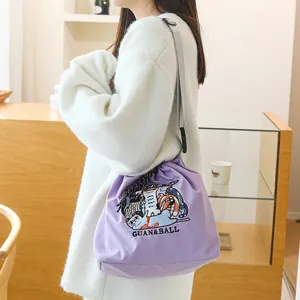 Vue latérale du sac à cordon violet brodé de dessins japonais porté par un modèle
