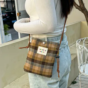 Stylish plaid wool crossbody bag for women featuring a woven strap and colorful text label detail
