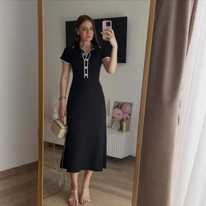 Vista de cuerpo entero de un elegante vestido midi negro de canalé con cuello polo blanco.