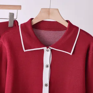 Dettaglio ravvicinato del top in maglia bordeaux con colletto bianco e bottoni a fiori