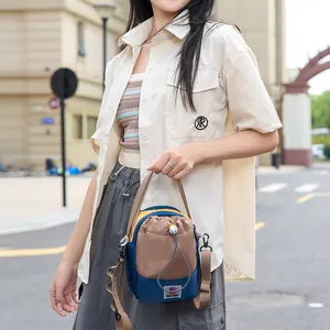 Mannequin asiatique tenant un sac à bandoulière d'extérieur multicolore à cordon en ville