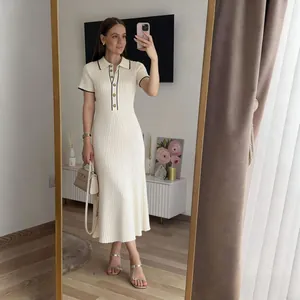 Detalle de vestido polo de punto beige con ribete negro en contraste y diseño entallado