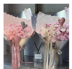 Dettaglio di bouquet di rose rosa decorati con cuori in pelle e lunghi nastri eleganti.