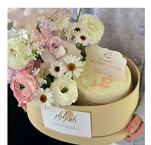 Detailed view of a round kraft paper gift box filled with fresh roses and daisies flowers