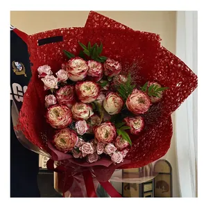 Primo piano di carta per fiori rossa testurizzata che avvolge un bouquet di rose da regalo