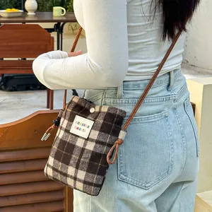 Close-up detail of a plaid wool crossbody bag featuring the sozakka beauté label.