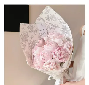 Primo piano di un bouquet di peonie rosa con un accessorio a cuore in pelle morbida