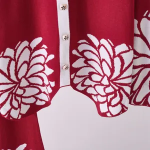 Dettaglio ravvicinato di un cardigan in maglia jacquard a fiori rossi e bianchi con bottoni